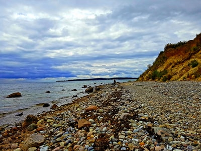 棕色岩石在海滨白云和蓝天白天
